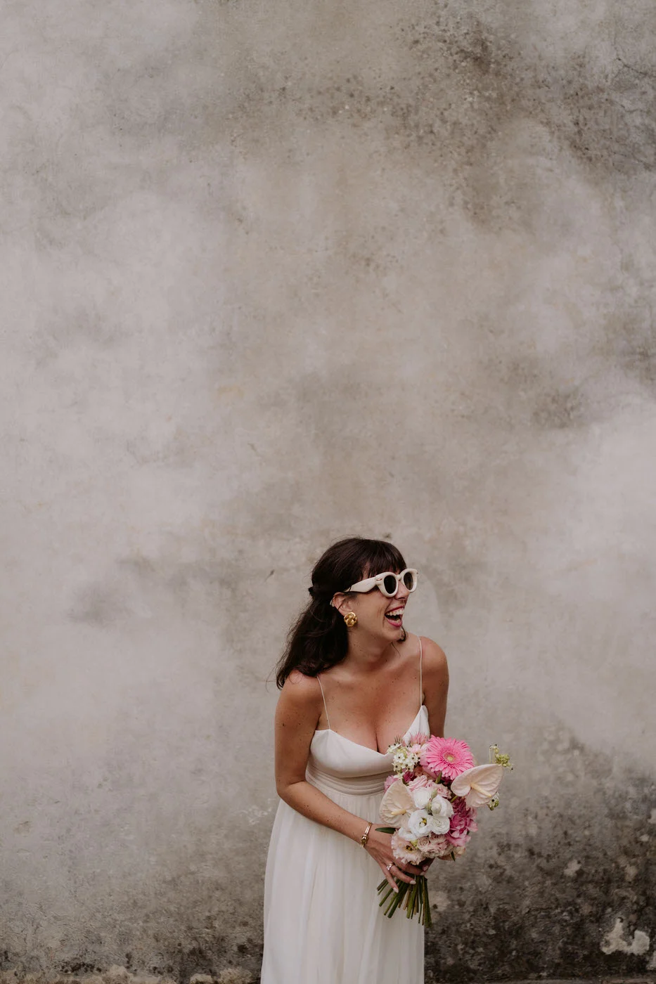 Bride laughing in white sunglasses with her bouquet, wedding at Villa Buonvisi in Tuscany