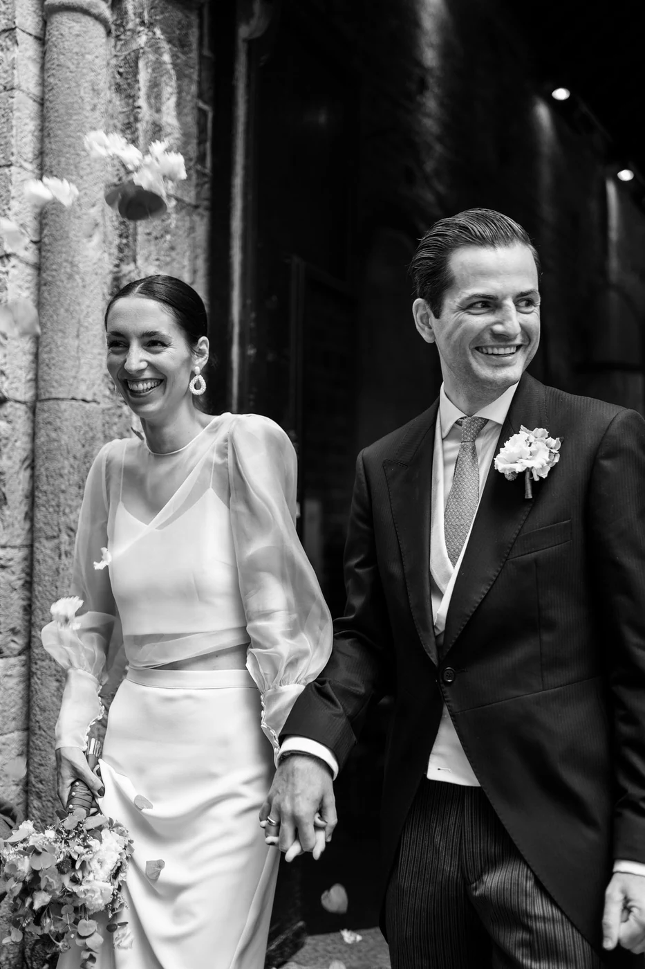 The couple smiling as they leave the church, in black and white