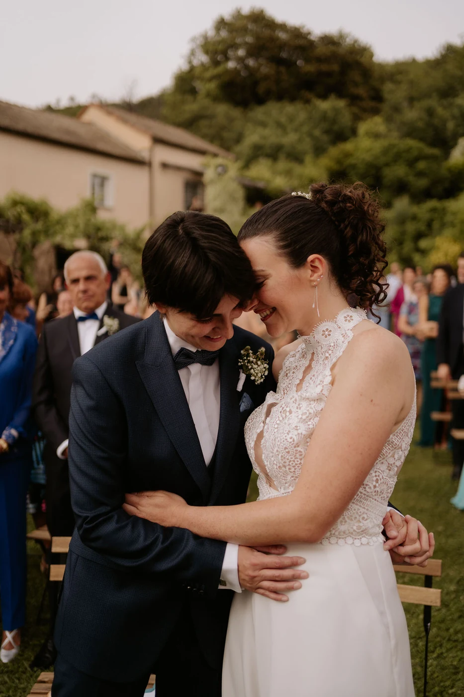 The two brides hug and smile during the outdoor ceremony
