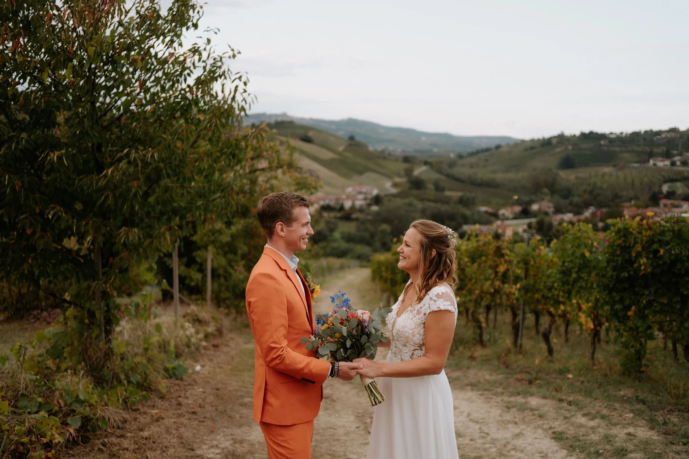 The couple holding hands among the vineyards of the Langhe