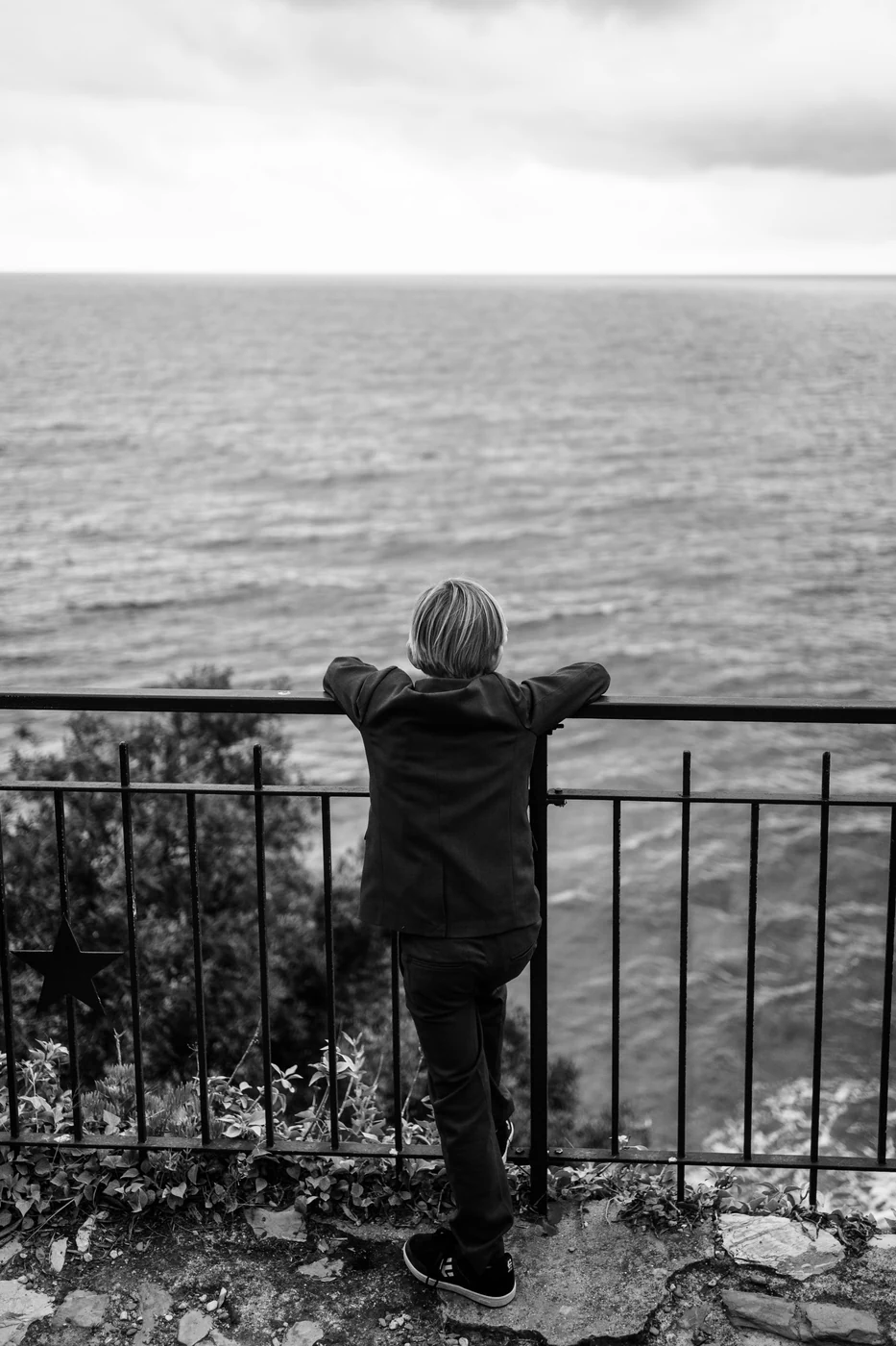 Little boy looking out at the sea from the terrace of Castello Canevaro, black and white photo