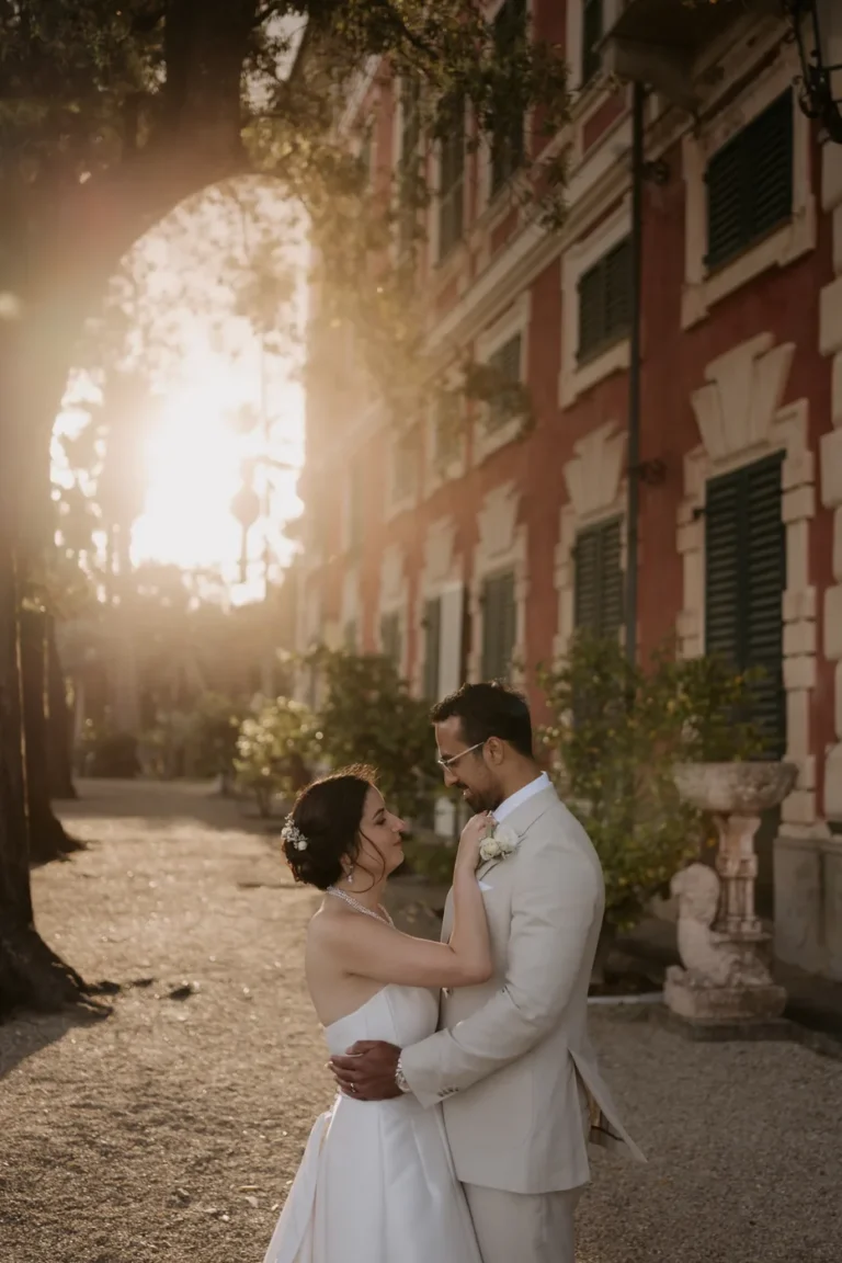 The couple embracing in the sunset light in front of Villa Durazzo