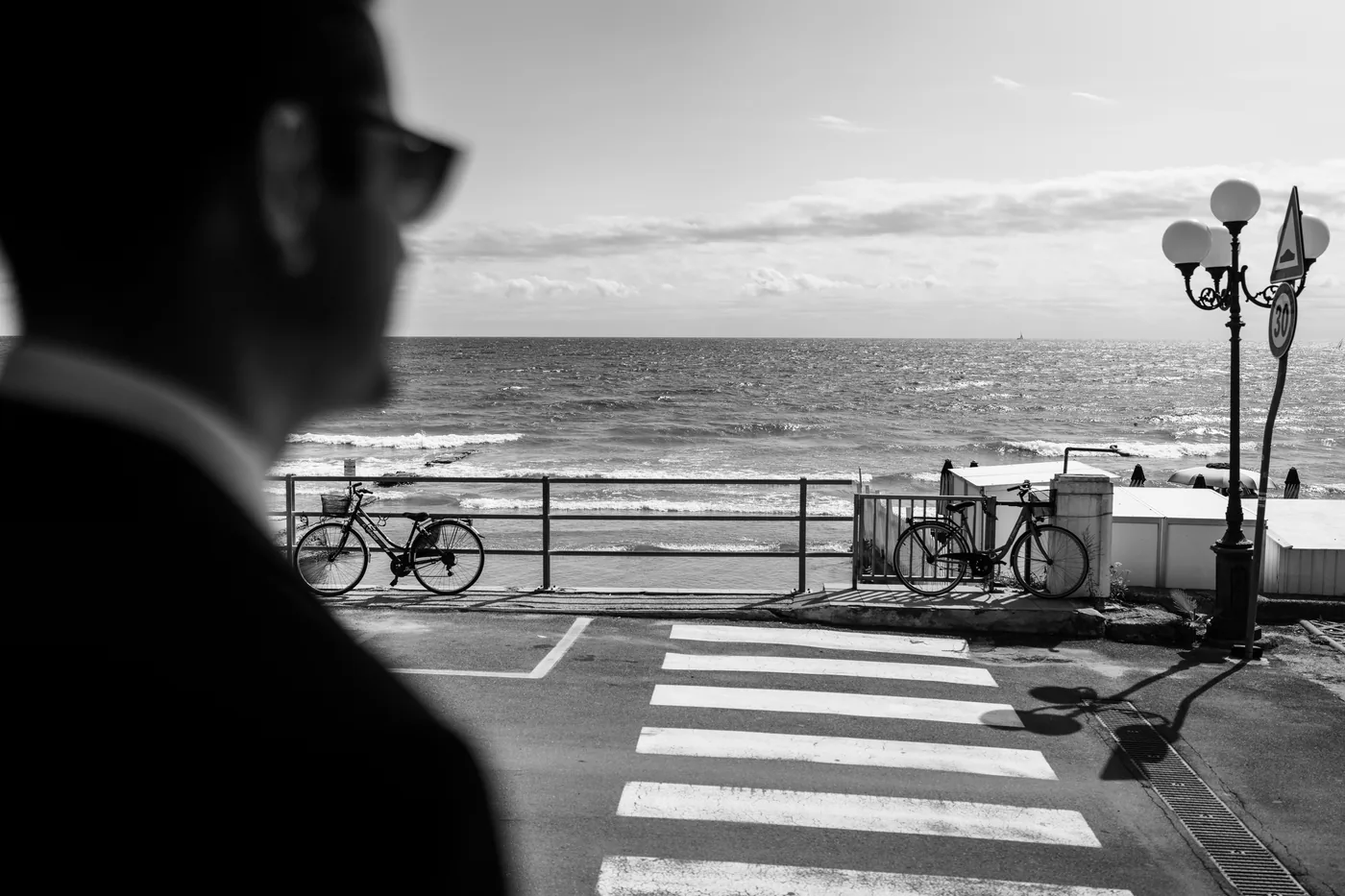 The groom looking out at the promenade with bicycles and a crosswalk, in black and white