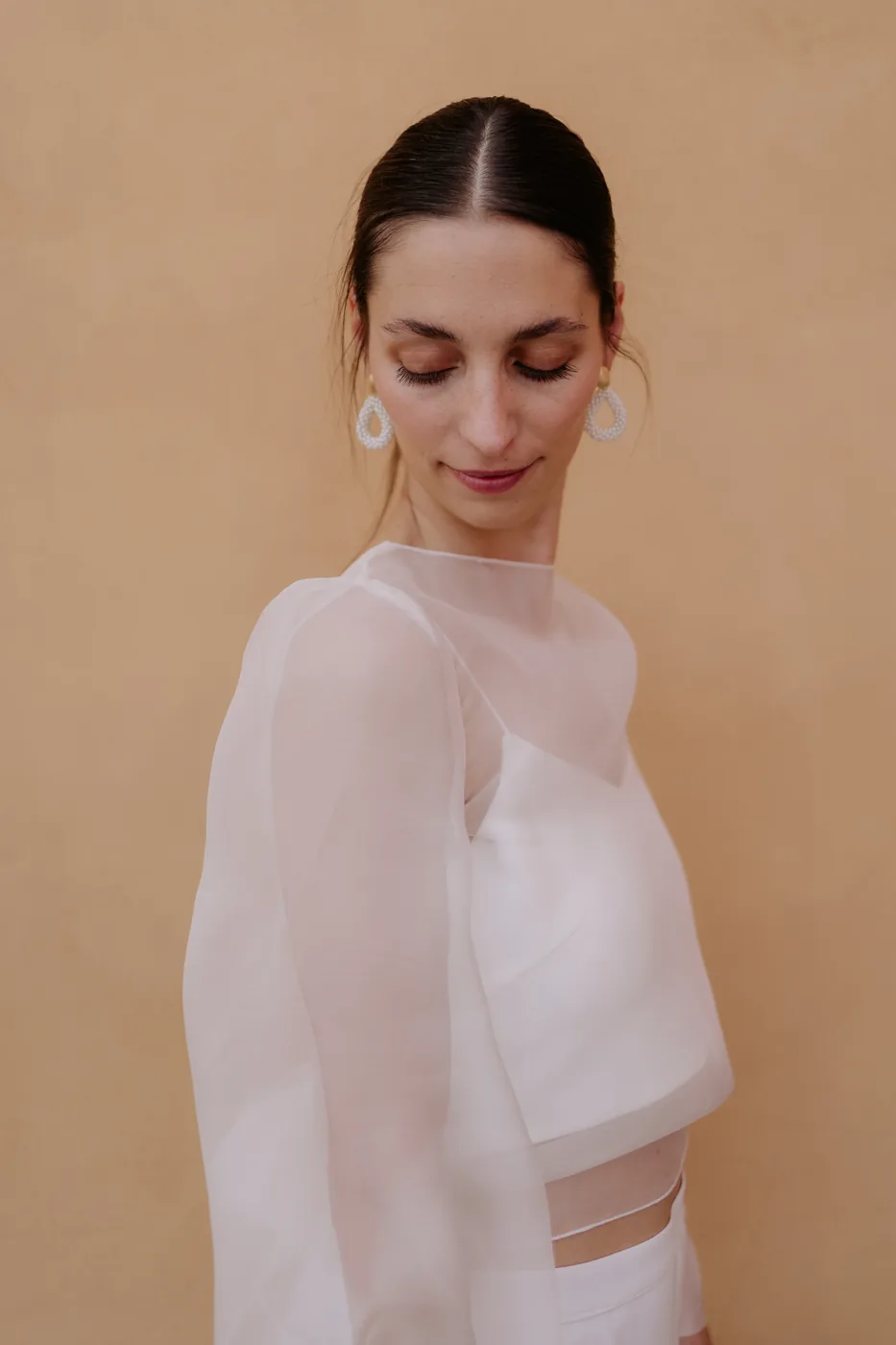 Portrait of the bride in her sheer blouse against an ochre wall