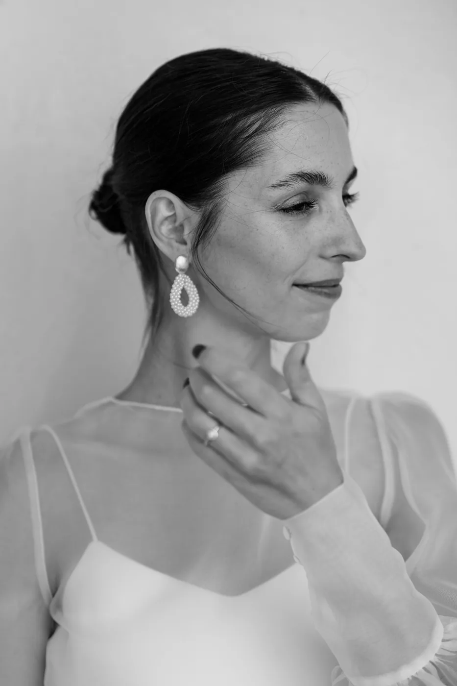 Close up of the bride with her drop earrings, in black and white
