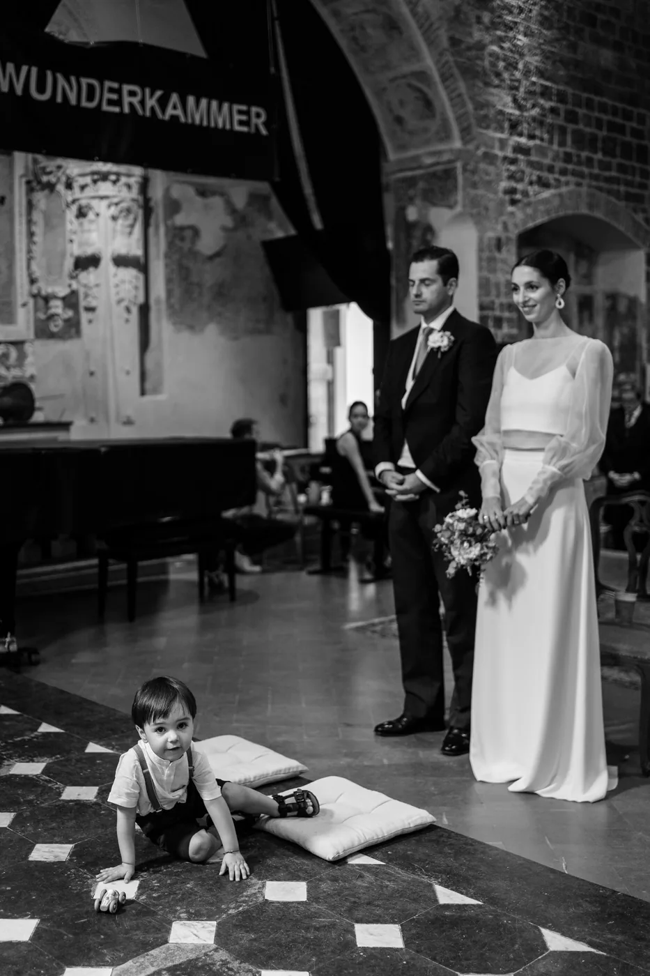 A child playing on the floor as the couple listens, in black and white