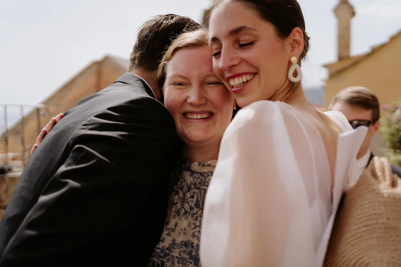 The bride hugging an emotional guest among the village rooftops