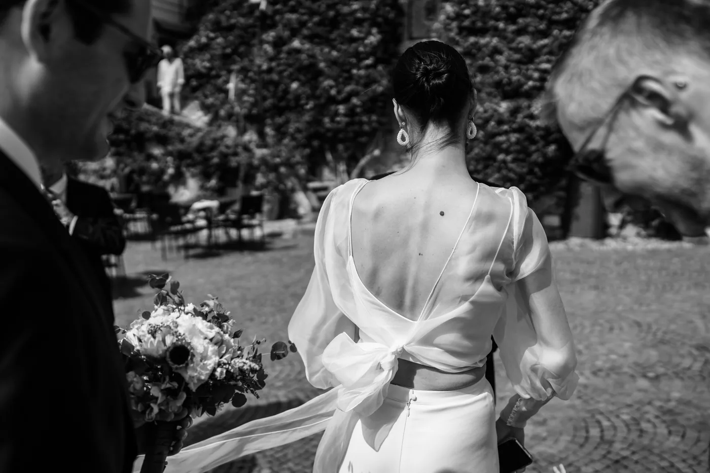 The bride from behind with the bow on her back, in black and white
