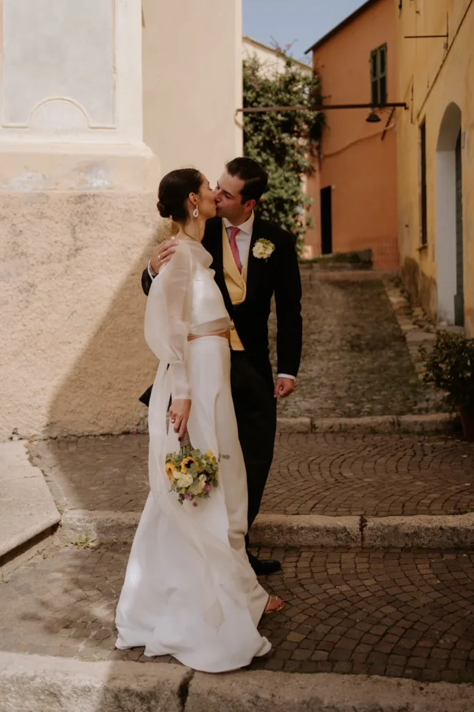 The groom kissing the bride in a lane in Cervo