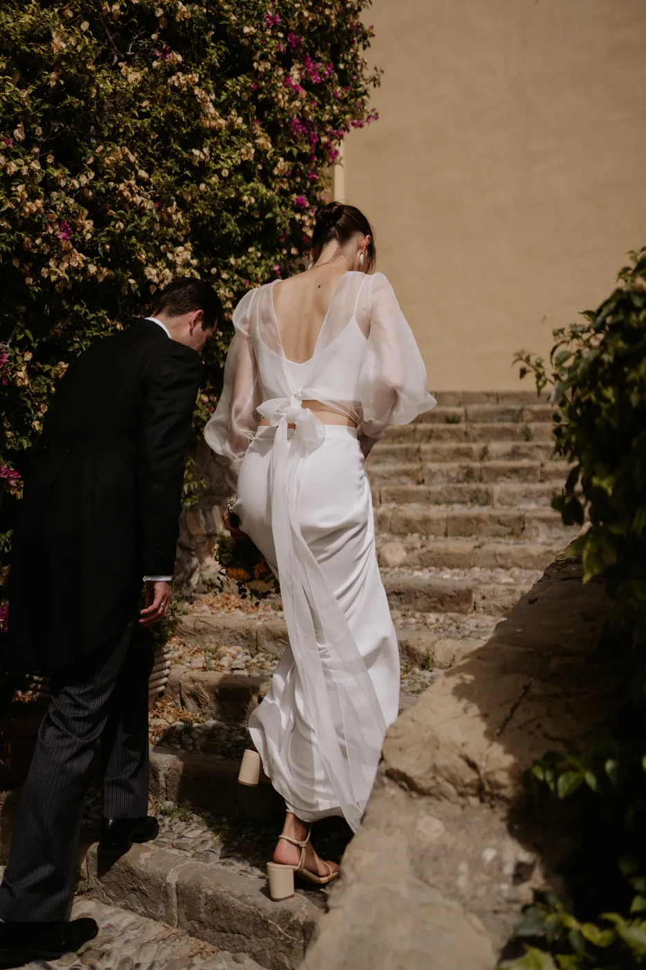 The couple climbing a stone staircase among flowers