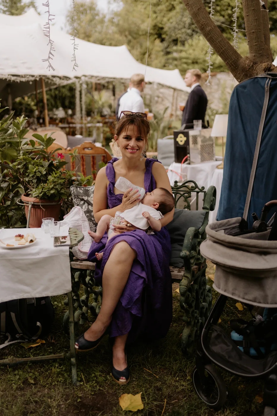 A guest in purple holding a baby among the garden tables