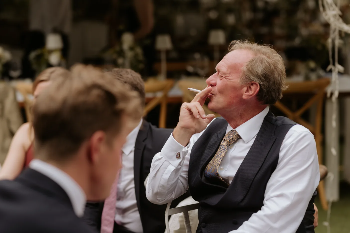 A guest smoking a cigar as he listens to a friend