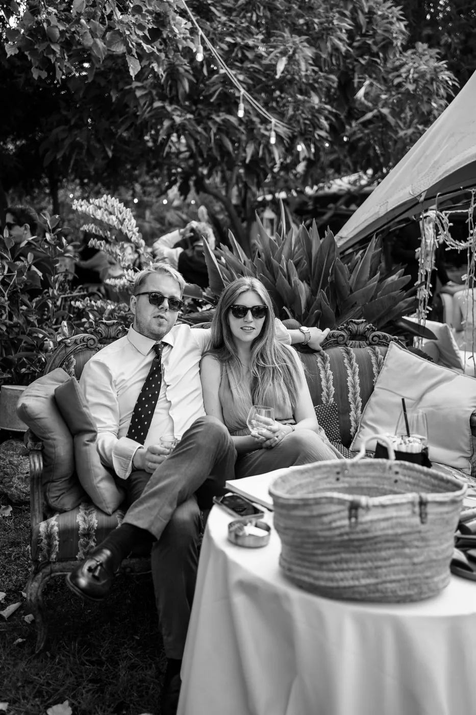 Two guests sitting on a sofa in the garden, in black and white