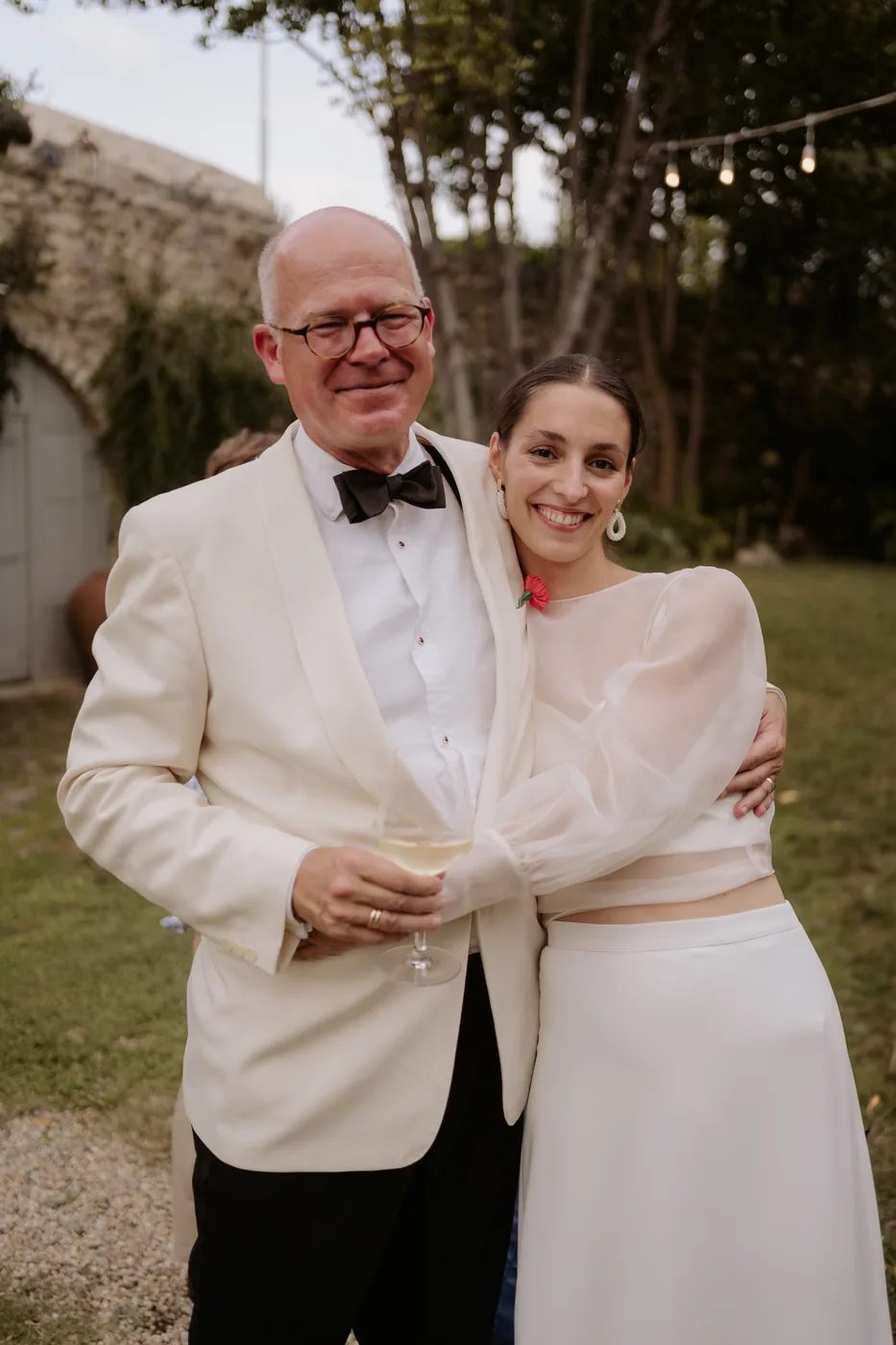 The bride hugging a guest in a white tuxedo