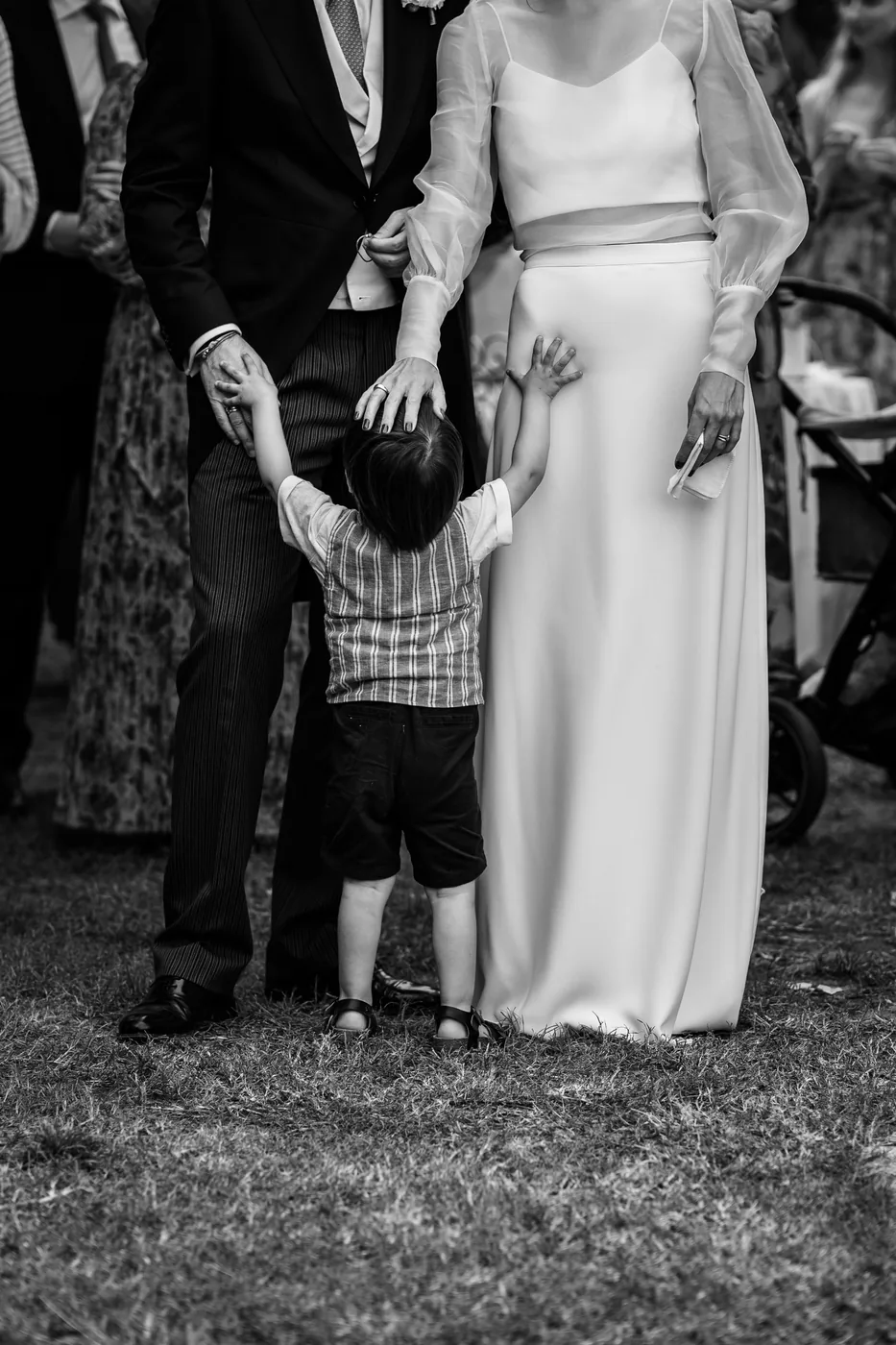 A child holding the bride's hand on the lawn, in black and white
