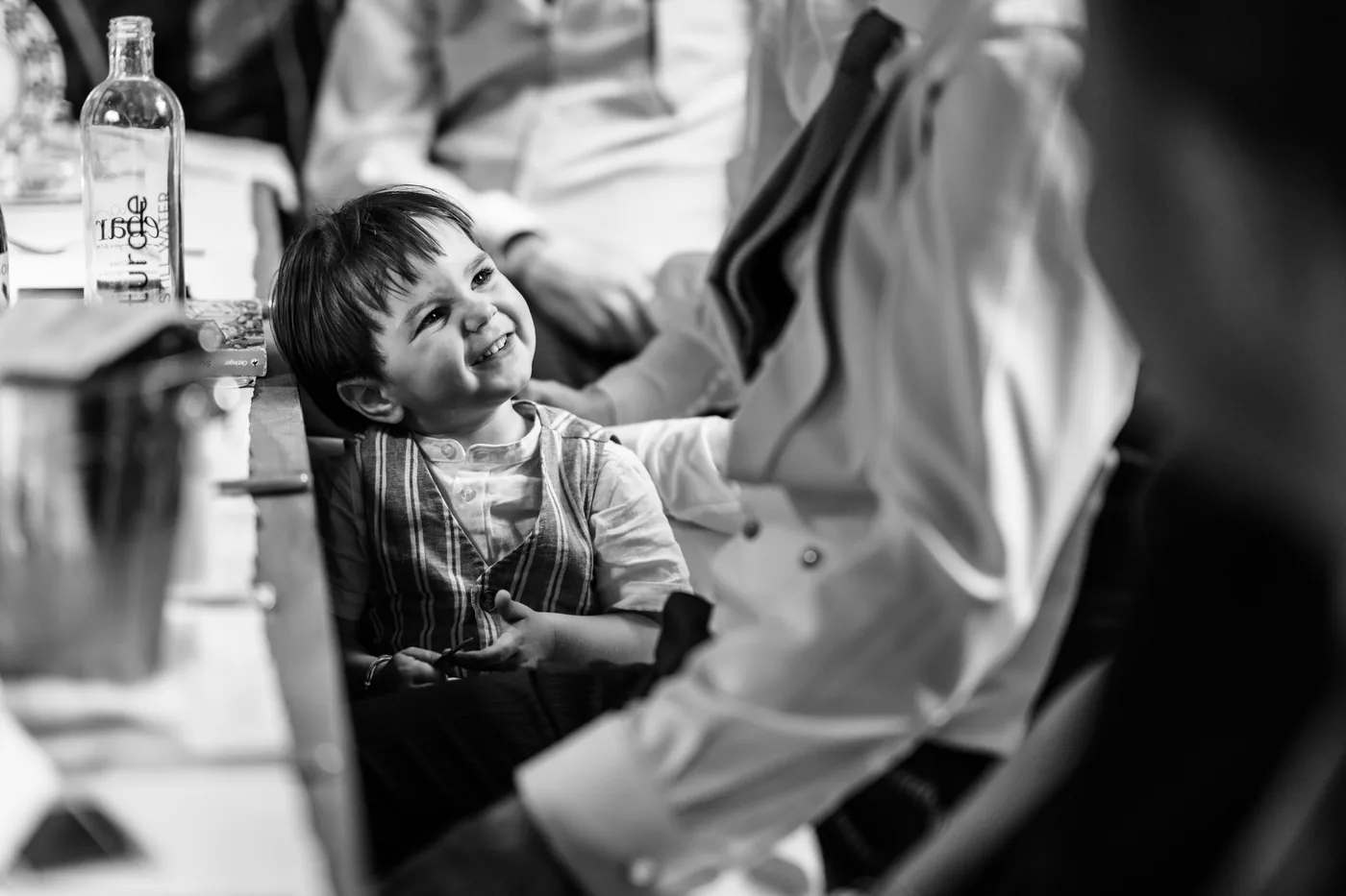 A child smiling at the table during dinner, in black and white
