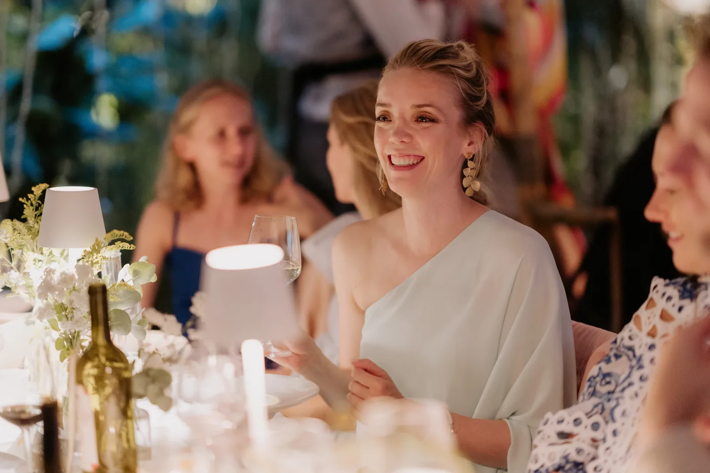 A guest smiling at the table among lamps and flowers