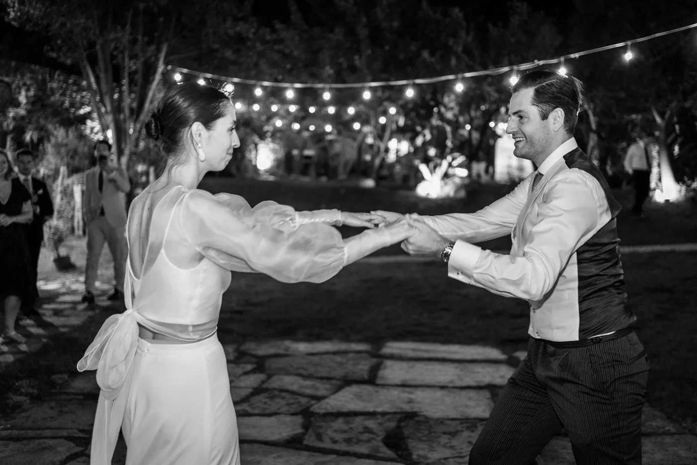 The couple's first dance under the string lights, in black and white