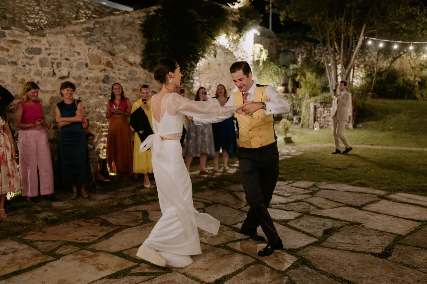 The couple dancing on the stone paving in front of their guests