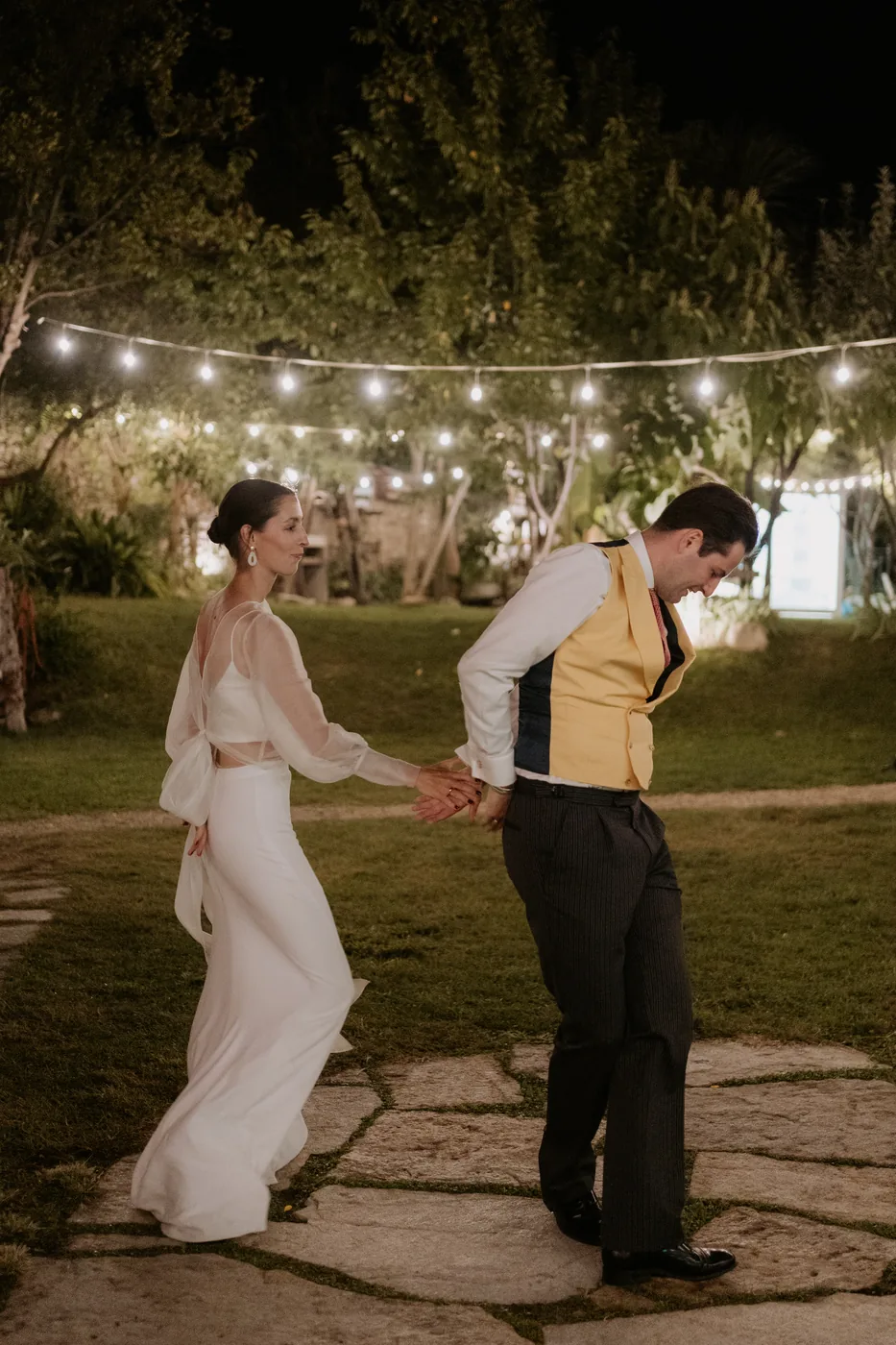 The couple dancing hand in hand in the garden in the evening
