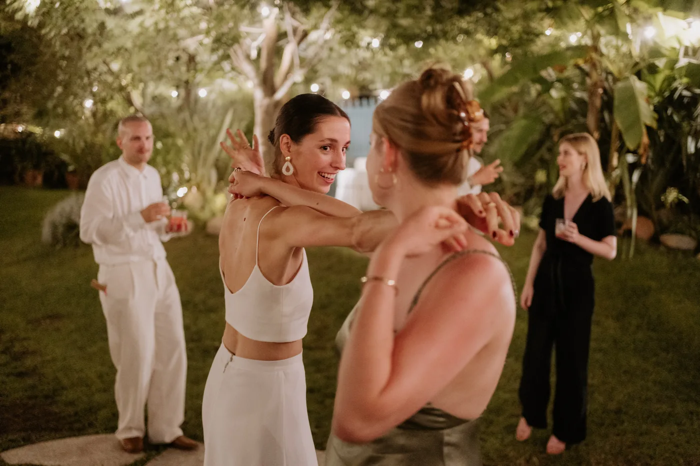 The bride hugging a friend as they dance in the garden