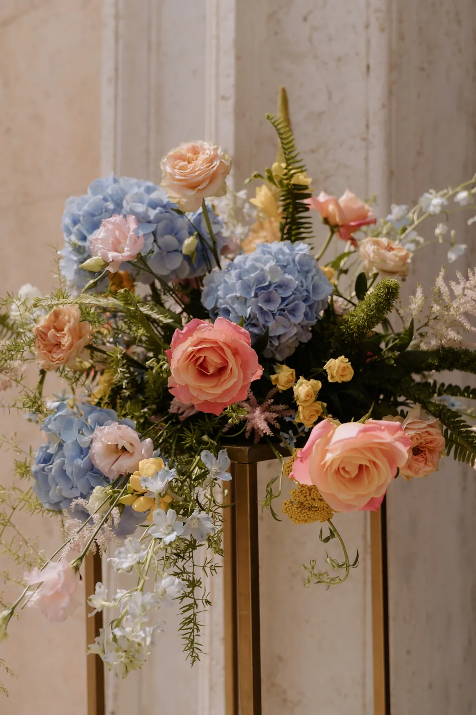 Arrangement of blue hydrangeas and peach roses at the church entrance