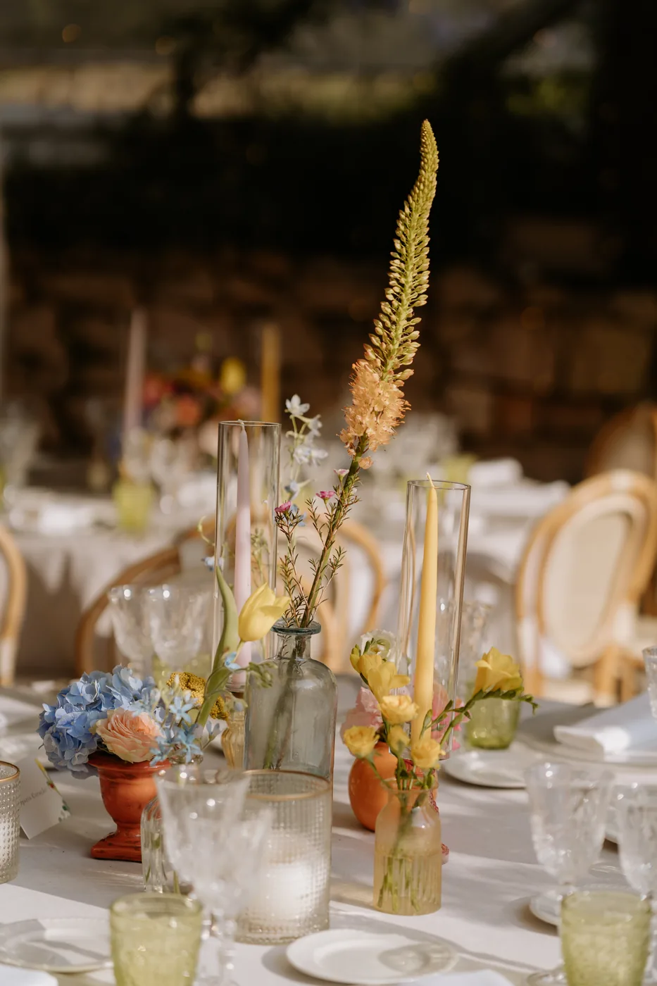 Table set with yellow flowers and colored glasses at sunset
