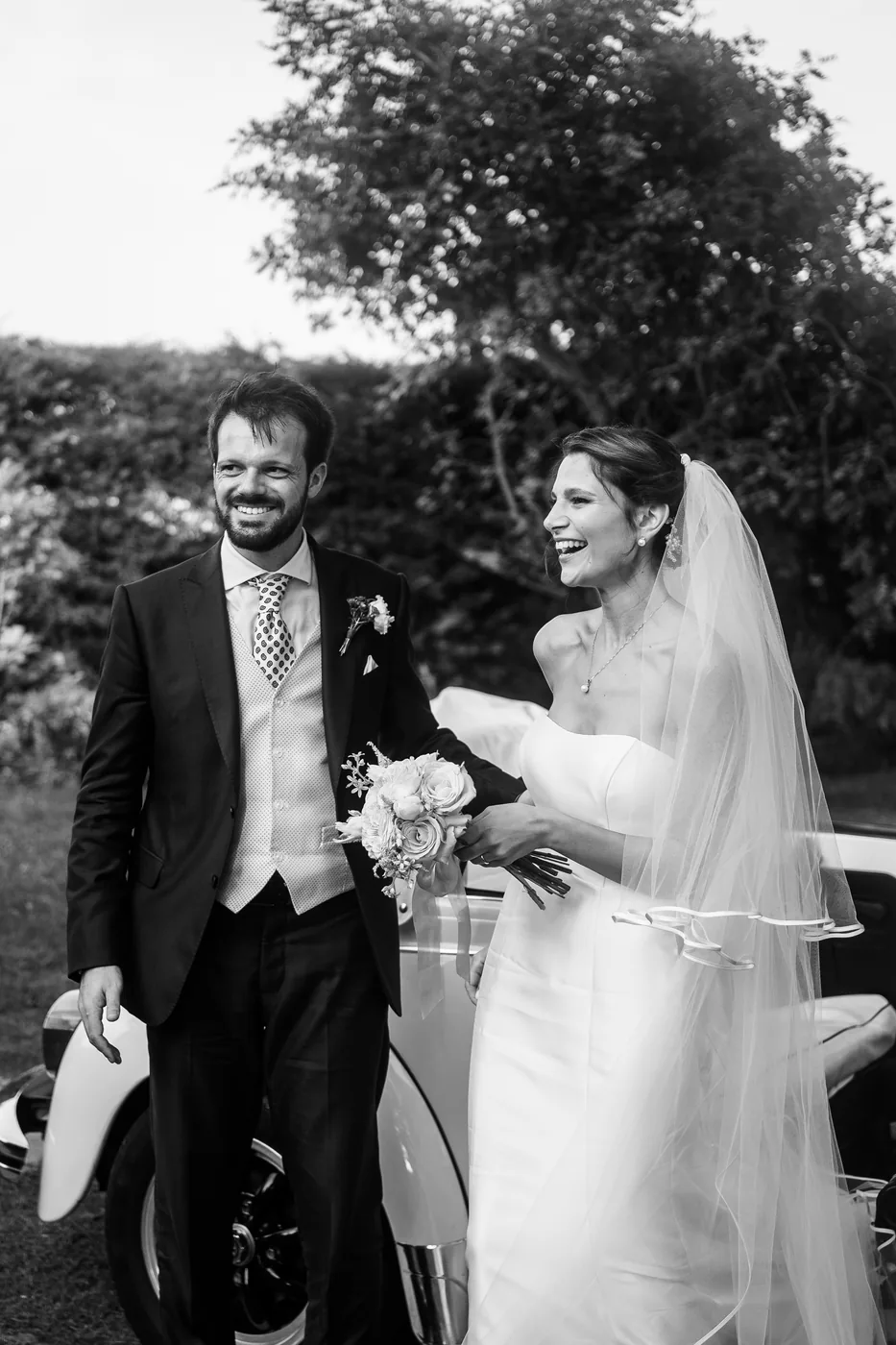 The couple laughing next to the Beetle, in black and white