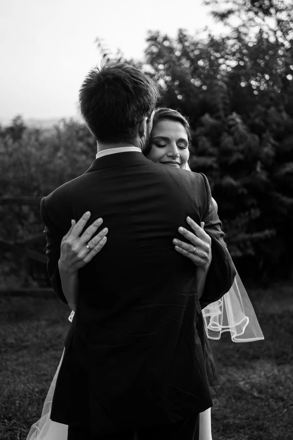 The bride hugging the groom in the garden, in black and white