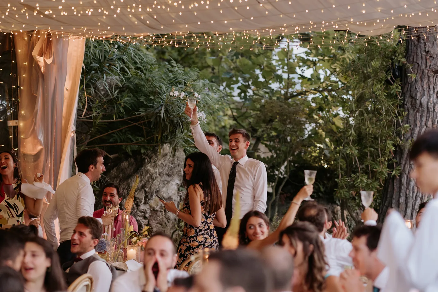 Guests on their feet celebrating under the lit pergola