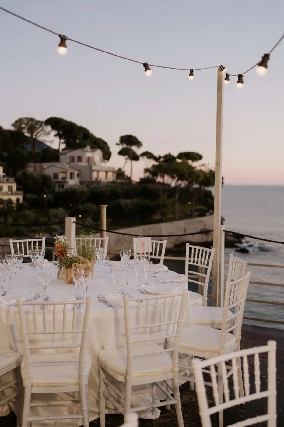 Outdoor tables under the lights with the sea at dusk